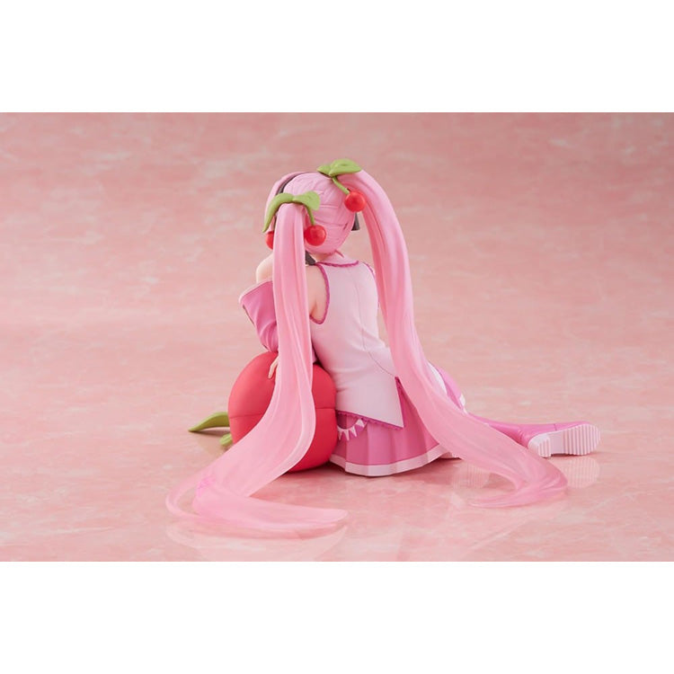 Hatsune Miku Sakura Miku Cherry Cushion Ver. figure by Taito sitting against a cherry cushion with pink Sakura-inspired colors.