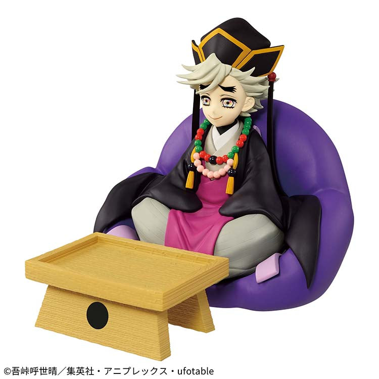 A three-quarter studio shot of the Banpresto FigLife! Doma accessory holder. The figure depicts the Upper Moon Two demon with his signature rainbow eyes and cult leader attire, sitting cross-legged on a large purple cushion base behind a textured yellow rectangular tray.
