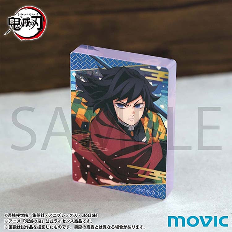A front-facing angled shot of the Giyu Tomioka acrylic block from the Demon Slayer Noble Art series. The block stands upright, showing the crisp character detail and the decorative blue-patterned border against a neutral background.
