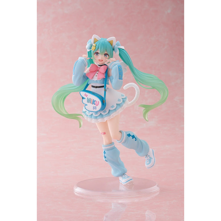 Front view of the Miku Fancy Ver. figure highlighting the large pink ribbon, white ruffed collar, and a blue wing-shaped "Miku" crossbody bag.