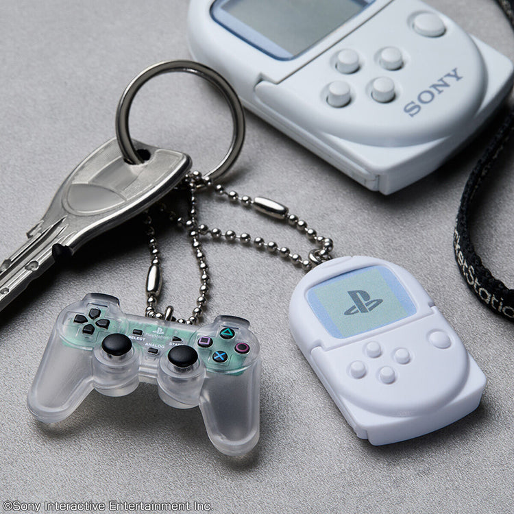 Sony PlayStation miniature DualShock controller and PocketStation charms on a keychain, part of a blind-bag collection.